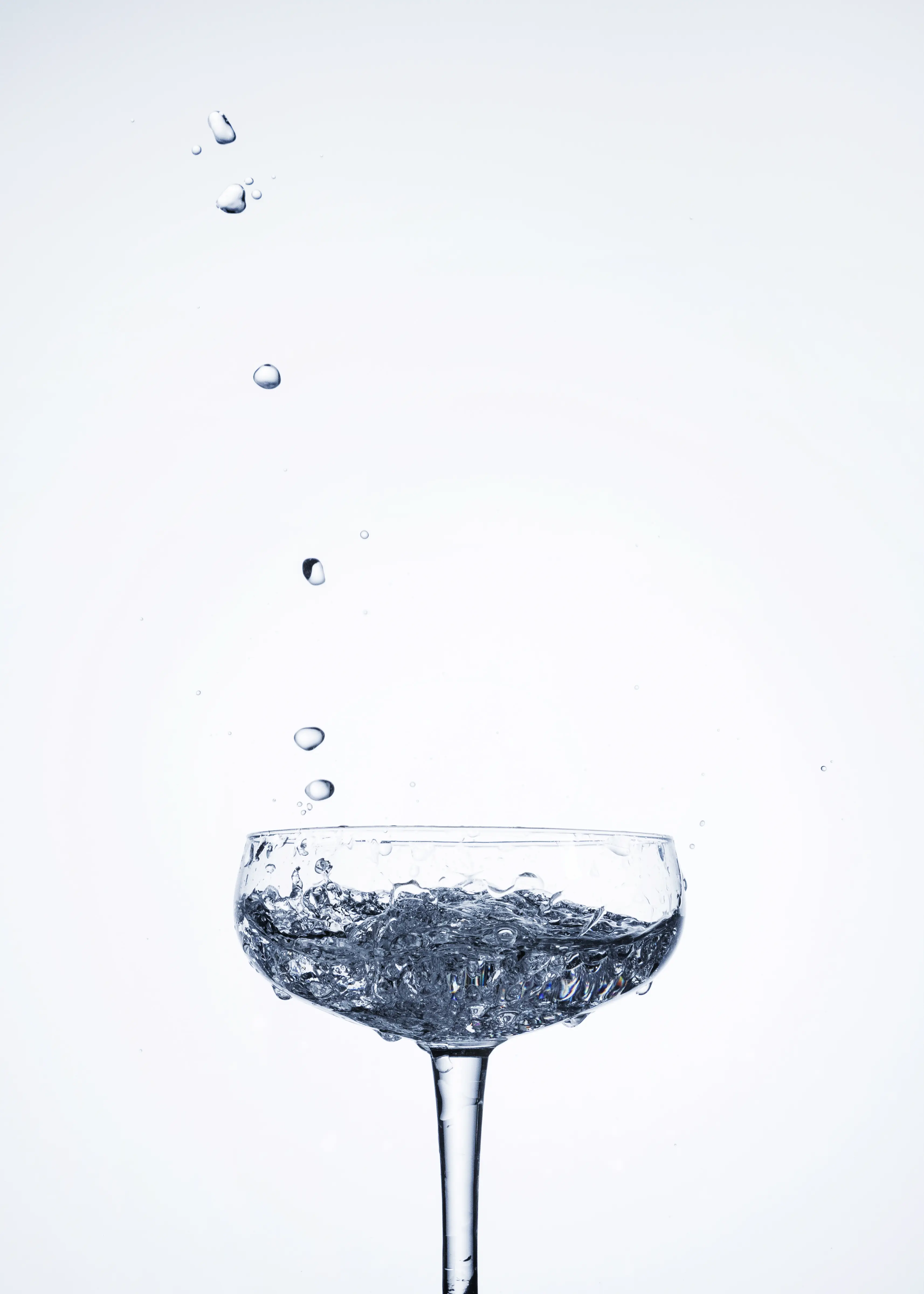 Clear water drops falling into a glass